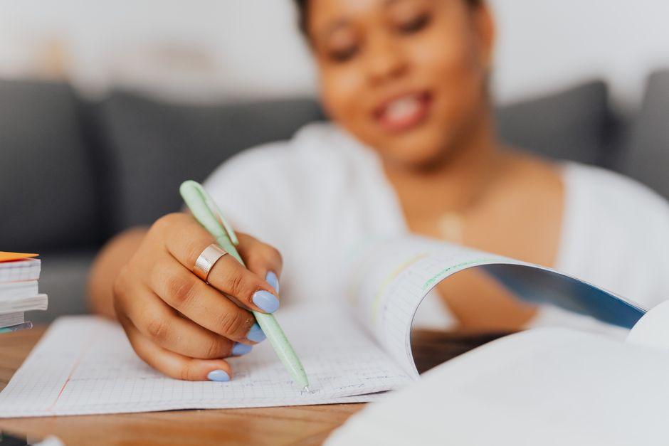 Comment organiser efficacement ses révisions avec de passer des examens en Belgique ? Élève organisant ses révisions dans un cahier avant des examens